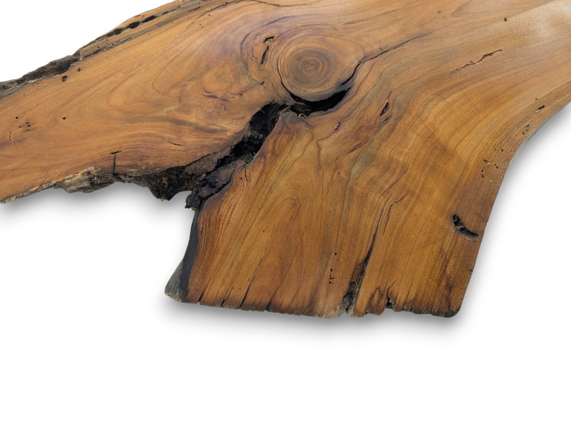 A close-up of a live edge wood slab with a prominent knot and dark cracks.