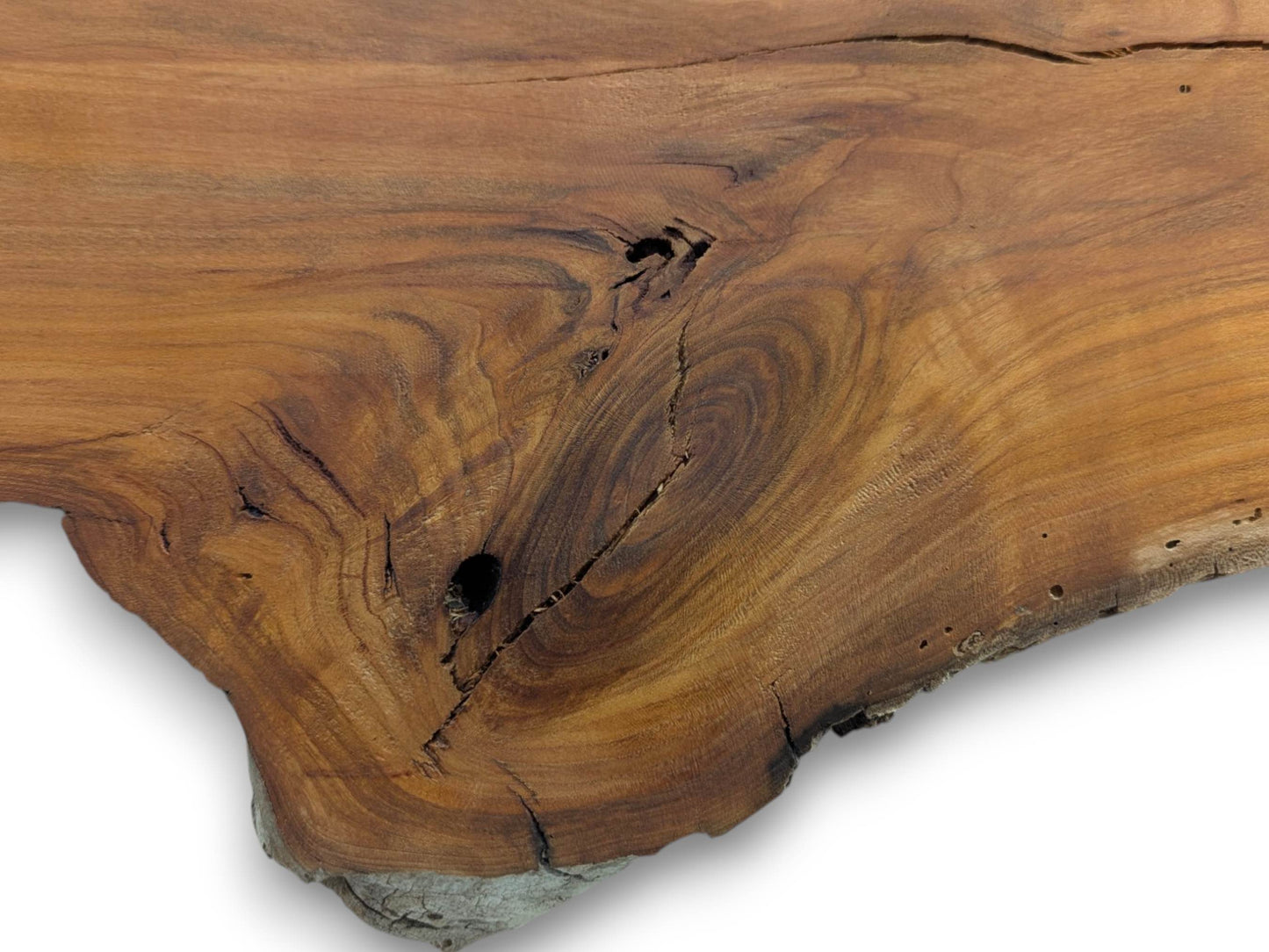 A close-up of a cherry wood slab with a live edge, prominent knots, and dark cracks.