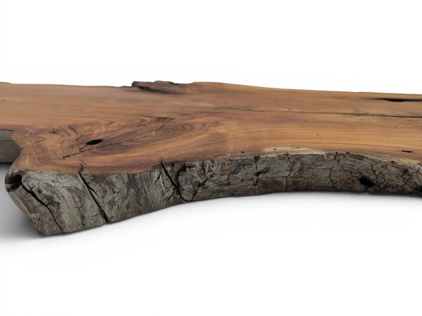 A close-up, low-angle view of a cherry wood slab with a natural live edge.