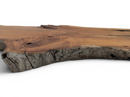 A close-up, low-angle view of a cherry wood slab with a natural live edge.