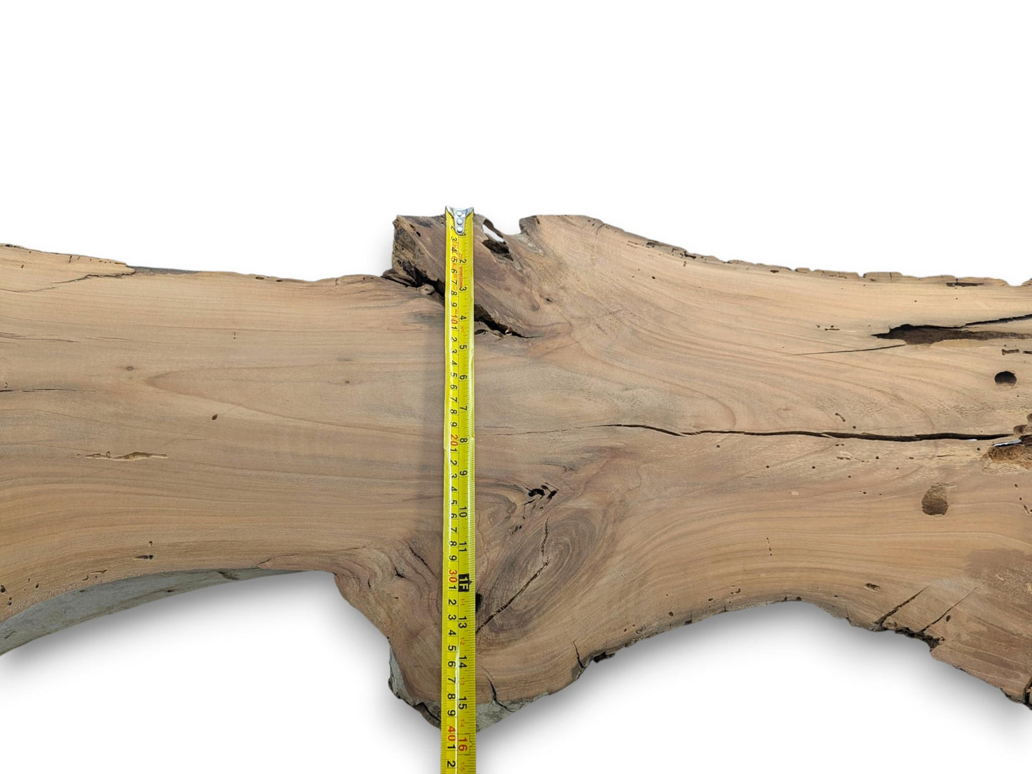 A cherry wood slab with a live edge, natural cracks, and a measuring tape.