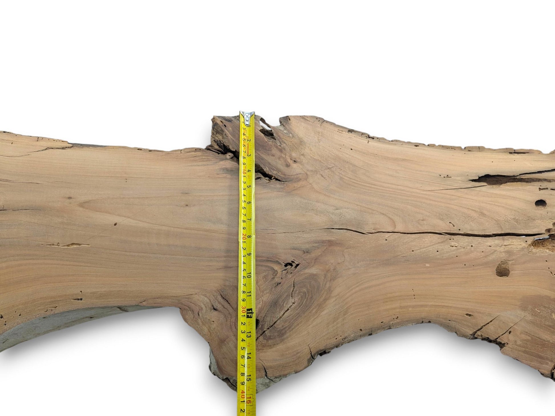 A cherry wood slab with a live edge, natural cracks, and a measuring tape.