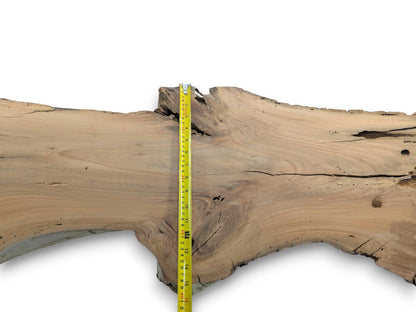 A cherry wood slab with a live edge, natural cracks, and a measuring tape.