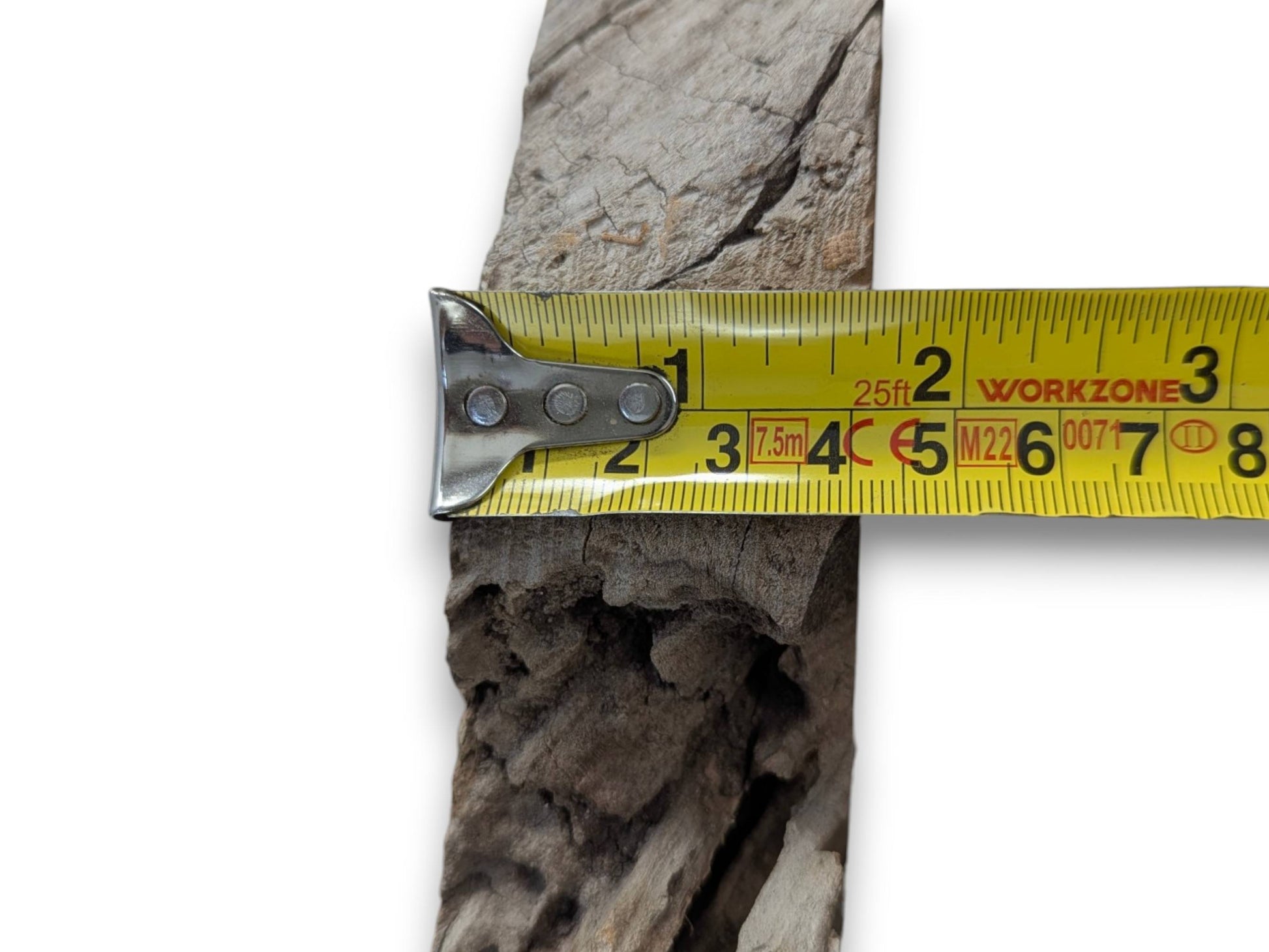 A yellow measuring tape across a light brown cherry wood slab with a live edge.