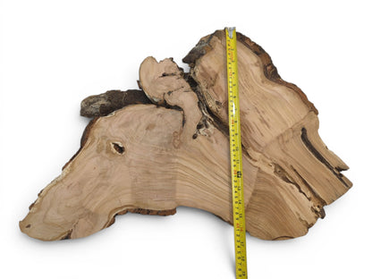A light brown wild cherry wood slab with a live edge and a yellow measuring tape.