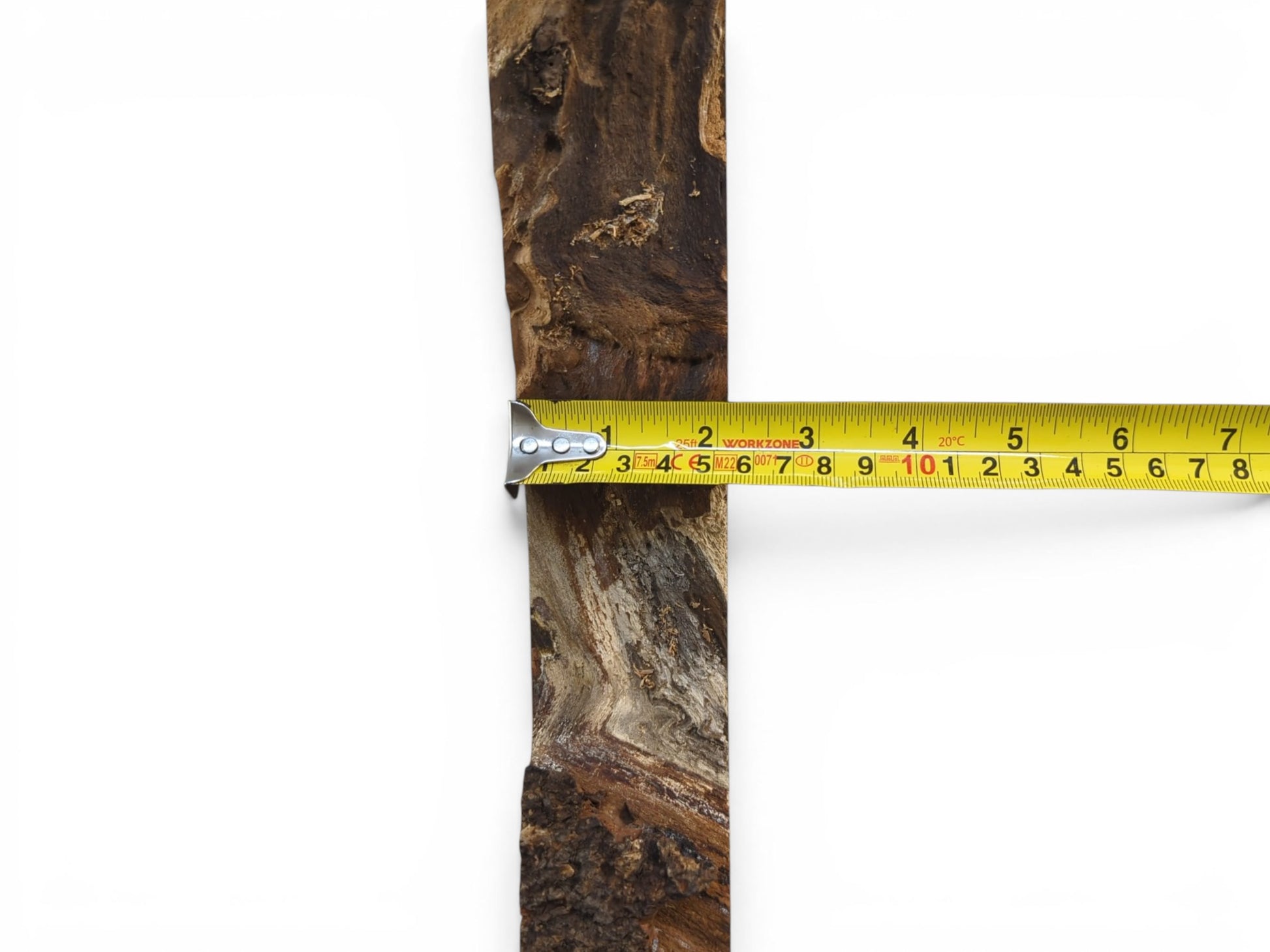 A close-up of a dark brown wood slab with a live edge and a yellow measuring tape.