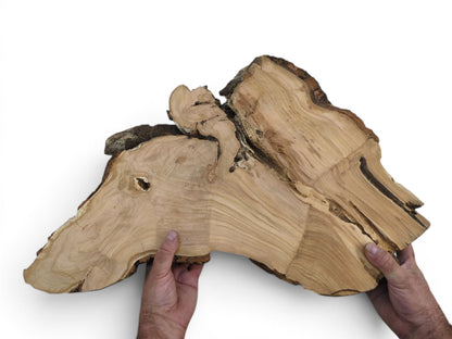 Two hands hold a large, light-colored wild cherry wood slab with live edges.