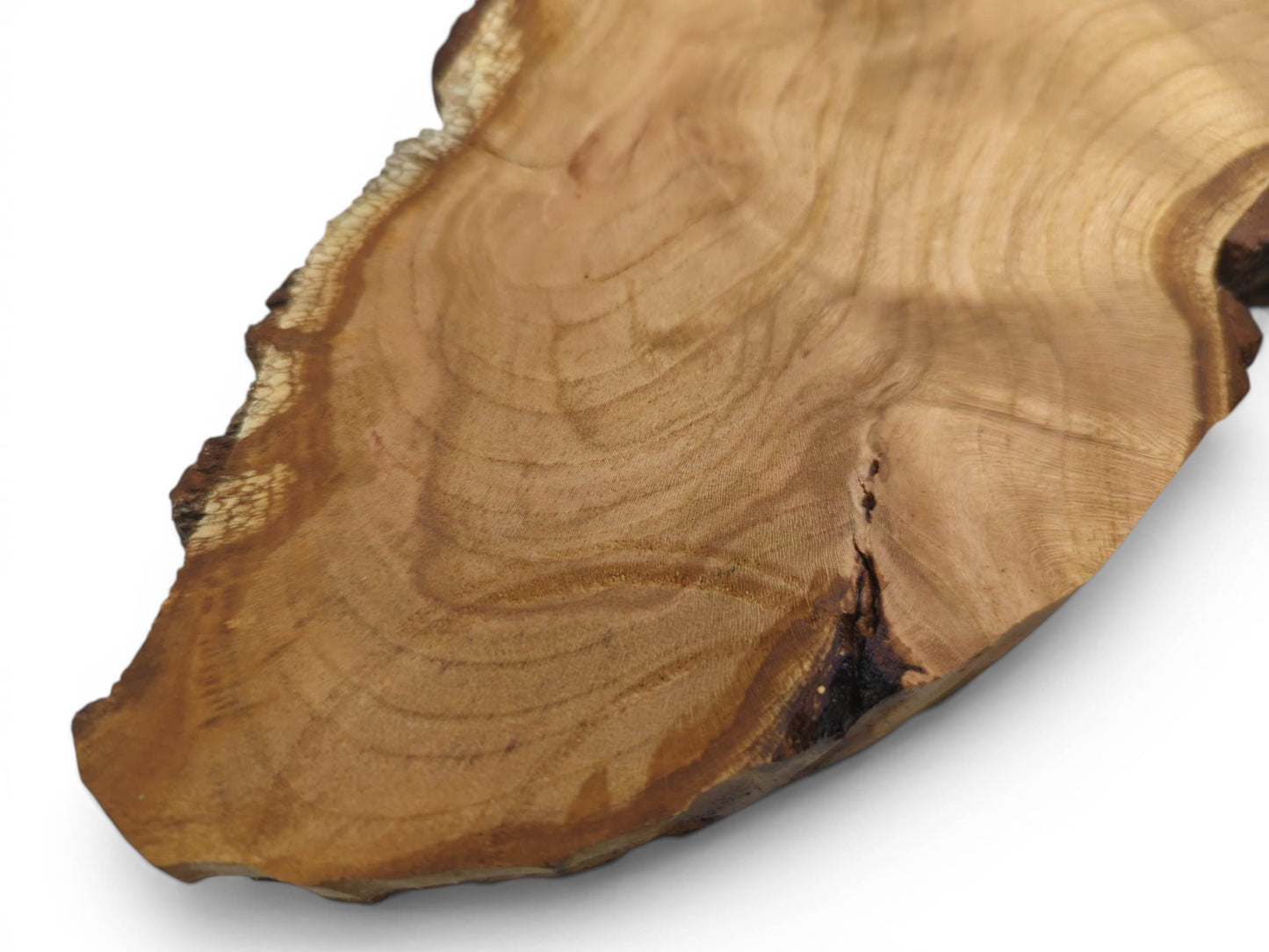 Close-up of a light brown wild cherry wood slab with a live edge and visible growth rings.