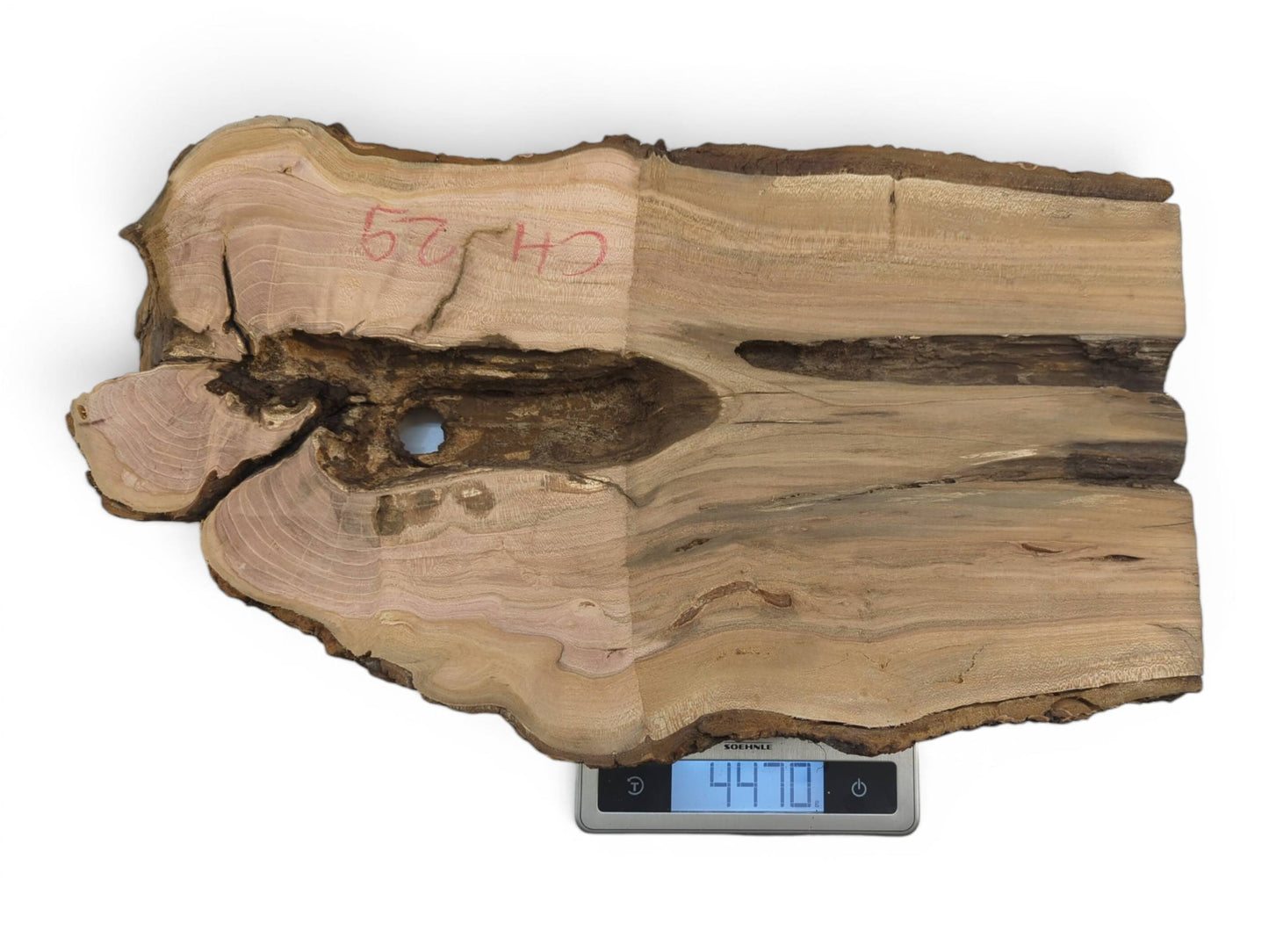 A light brown wild cherry wood slab with a live edge and a natural hole.