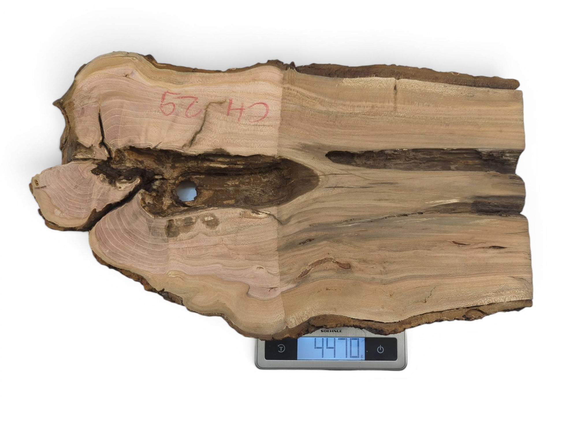 A light brown wild cherry wood slab with a live edge and a natural hole.