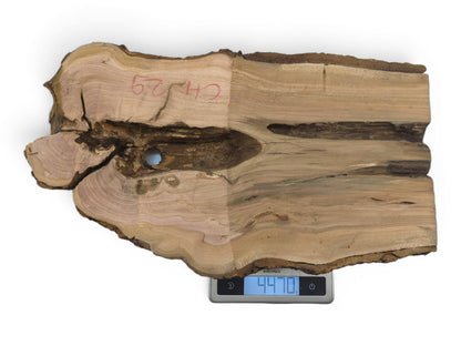 A light brown wild cherry wood slab with a live edge and a natural hole.