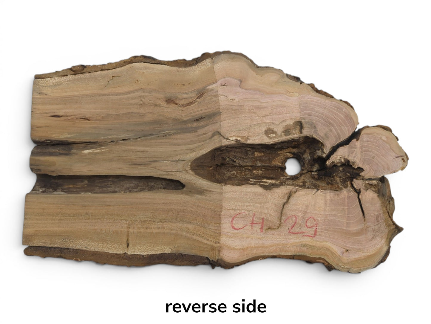Reverse side of a cherry wood slab with natural bark edges, a central hole, and cracks.