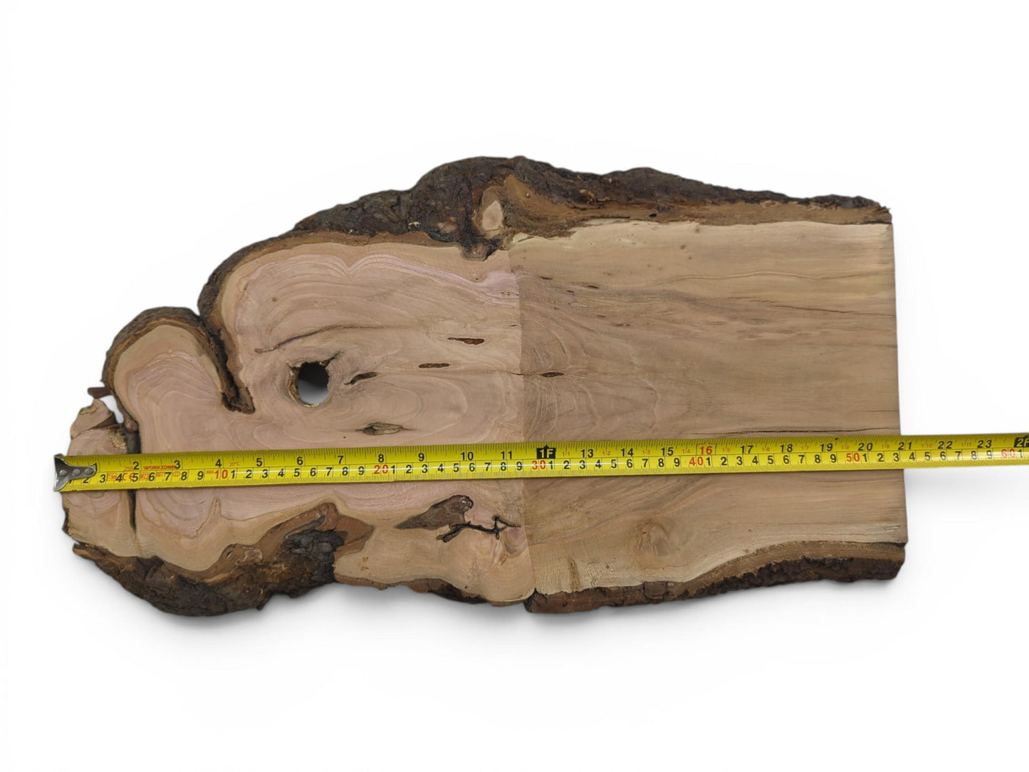 A wild cherry wood slab with a live edge and a measuring tape across its width.