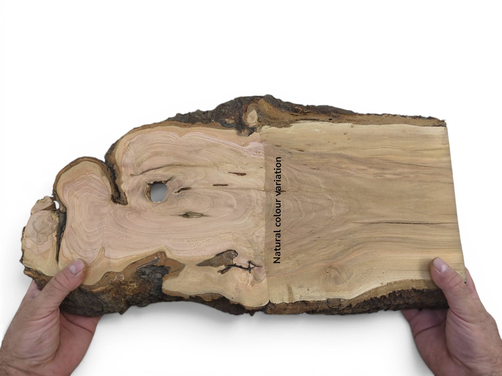 Hands holding a live edge cherry wood slab with natural color variation and a hole.