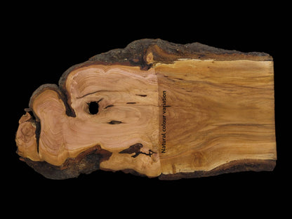 A live edge cherry wood slab with natural color variation, bark, and a central hole.