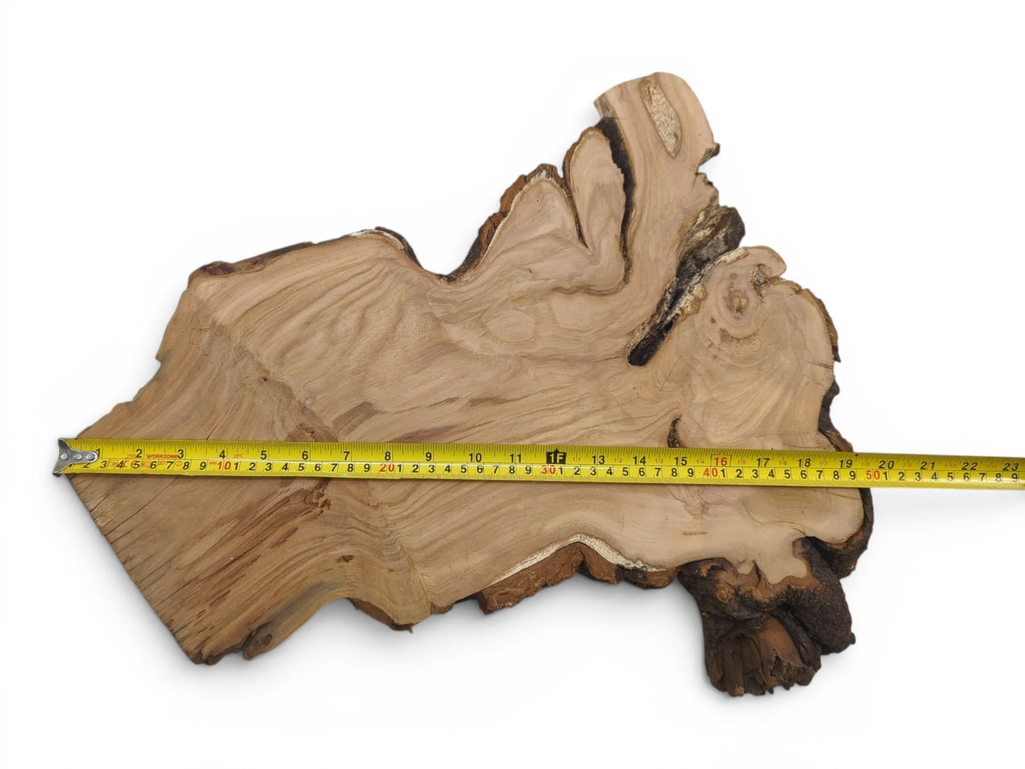 A light-colored, irregularly shaped wild cherry wood slab with a measuring tape across it.