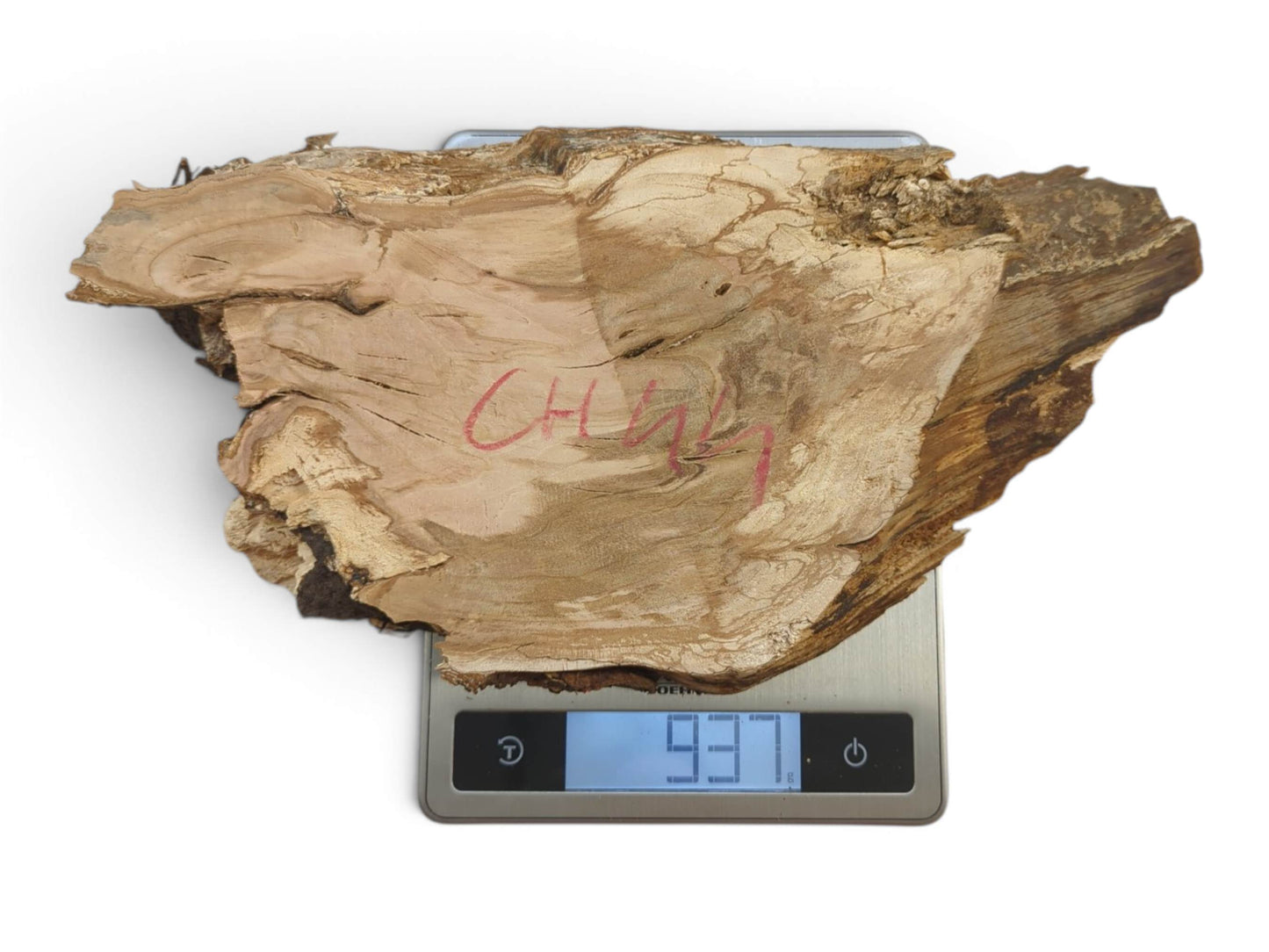 A light brown, irregularly shaped cherry wood slab with a live edge, resting on a scale.