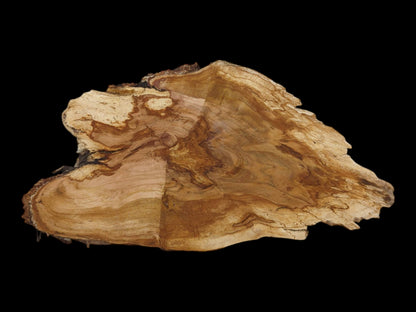 An irregularly shaped wild cherry wood slab with a light brown, wavy grain on a black background.