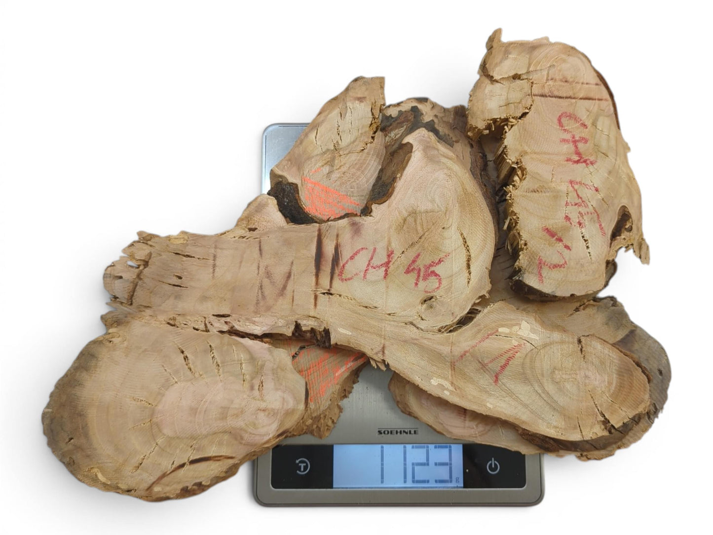 Top-down view of several raw wild cherry wood slices with red markings on a scale.