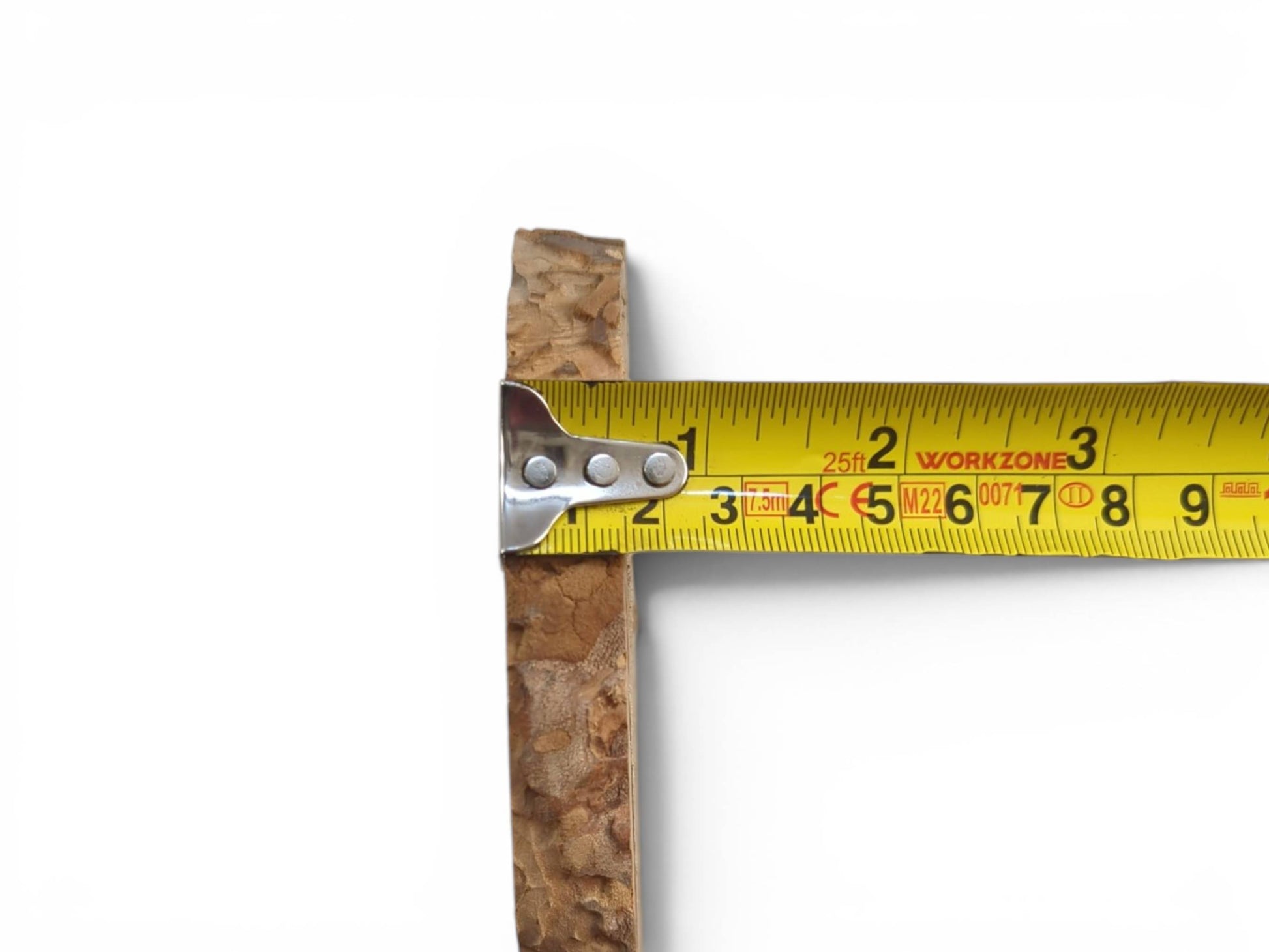 A tape measure against the rough, natural edge of a light brown wood piece.