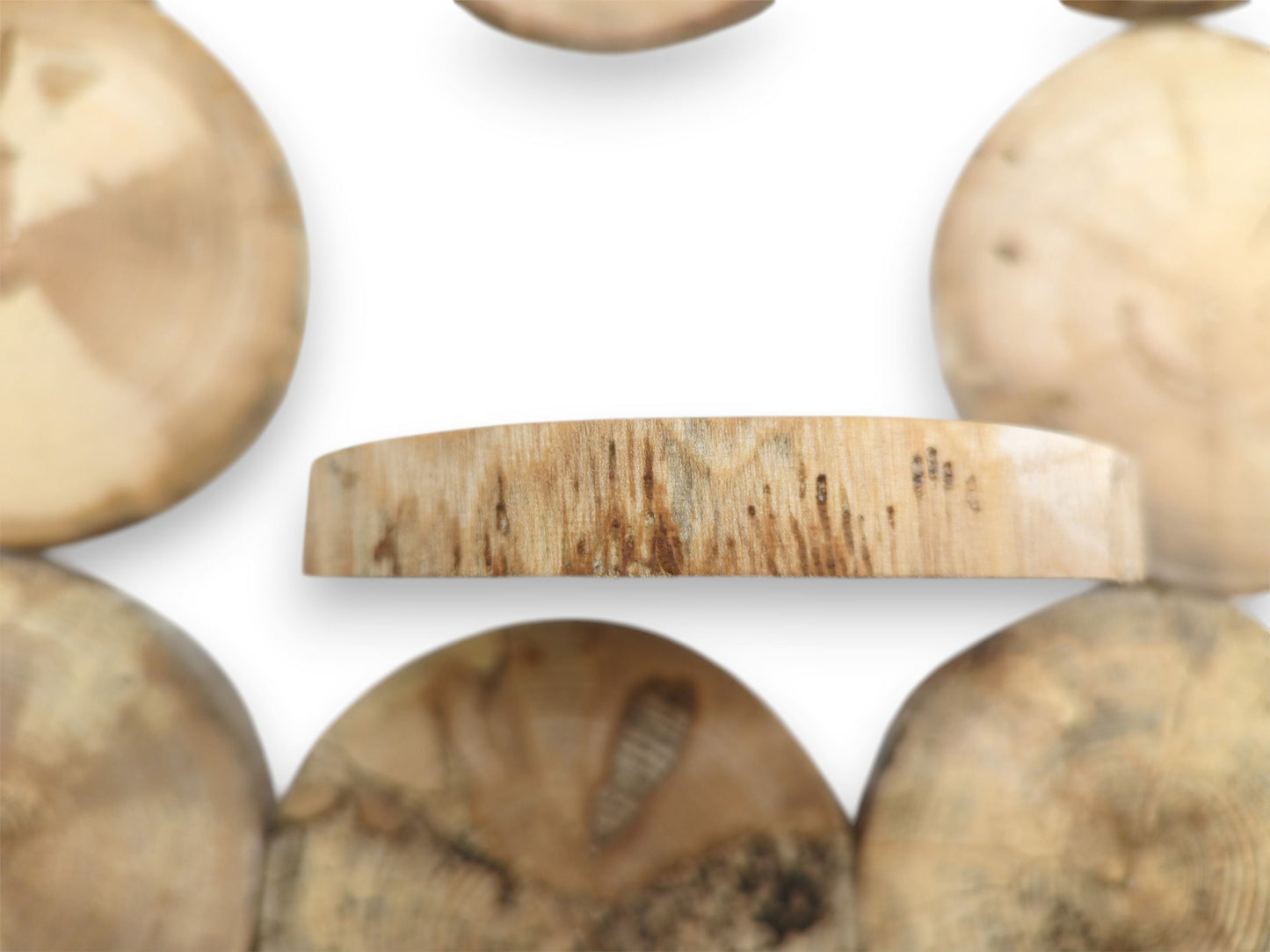 A central timber plank's edge shows vertical grain and dark markings against blurred rounds.