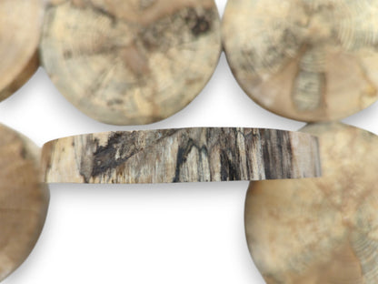 A spalted timber slice's edge reveals dark, vertical striations against a hazy, circular background.