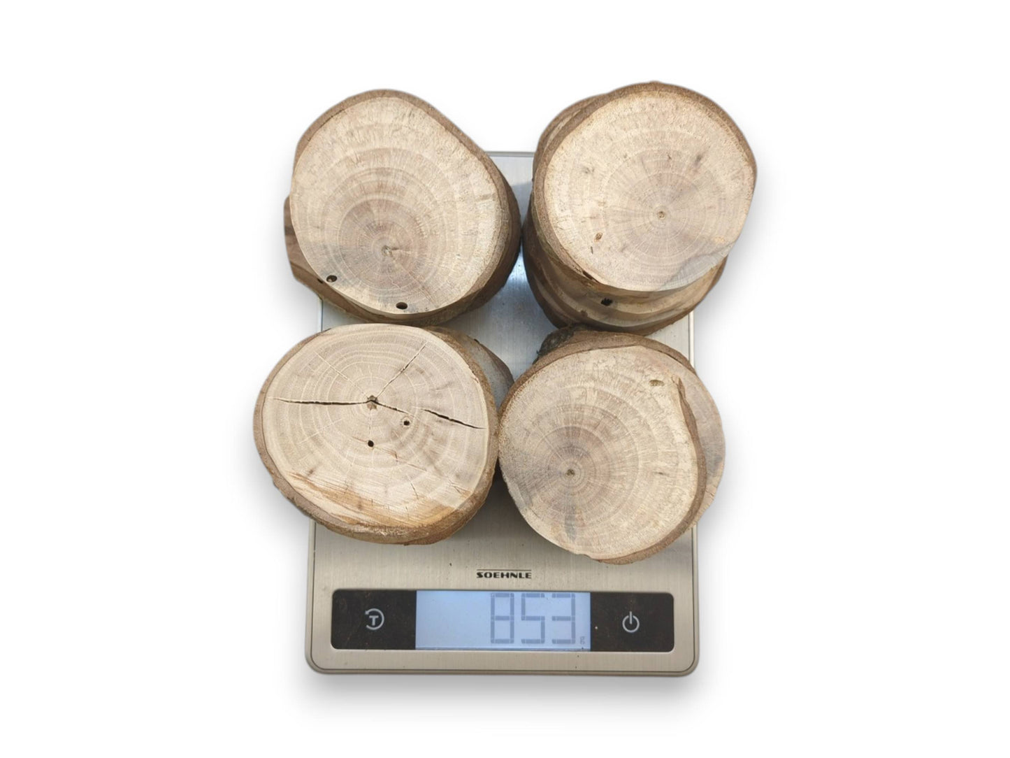 From above, four stacks of ringed timber discs are weighed on a digital scale.