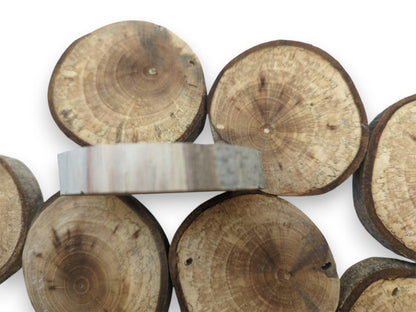 A single pale, planed timber slice rests sideways atop a cluster of bark-edged rounds.
