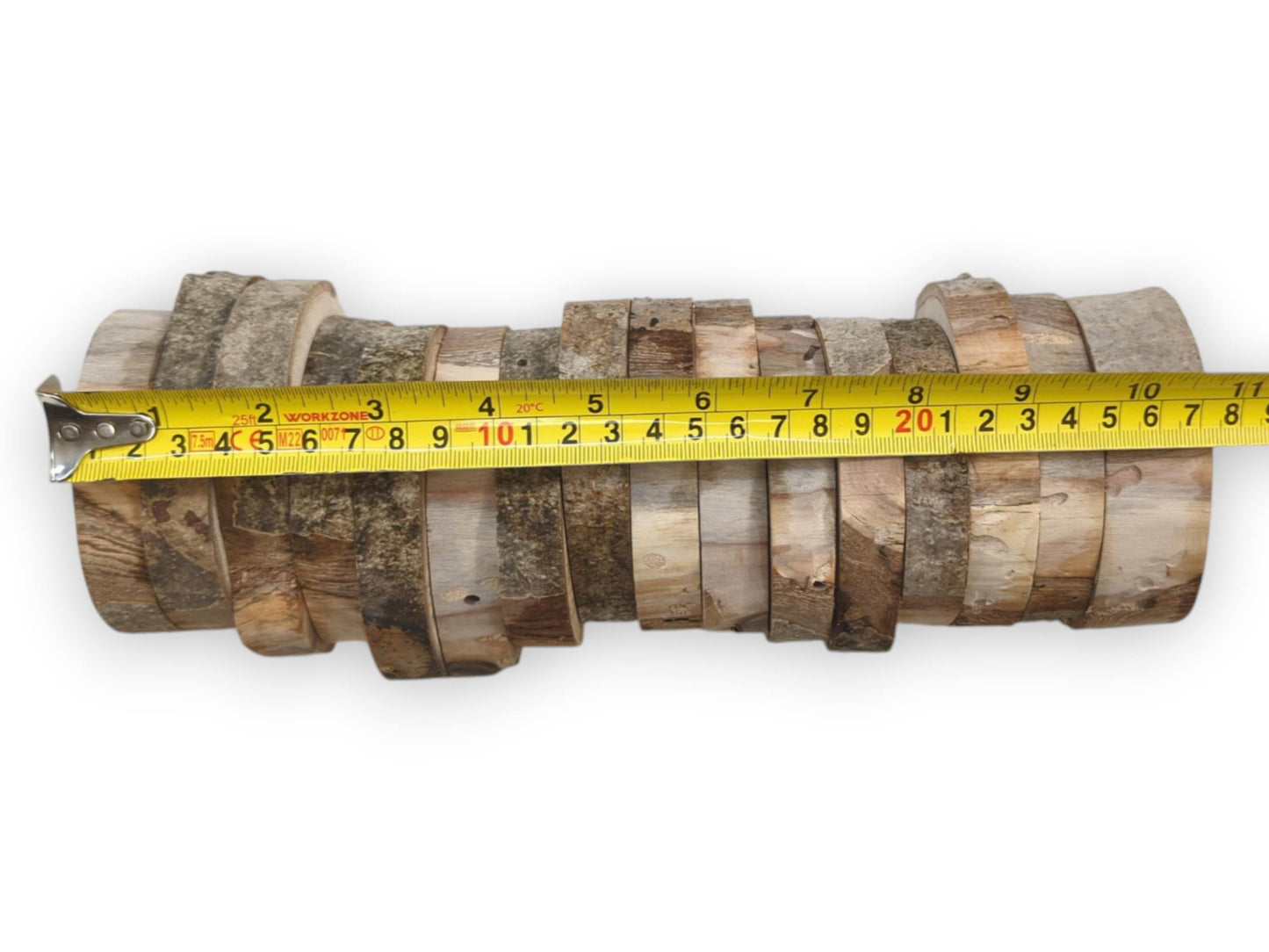 A yellow tape measure sizes a horizontal stack of sixteen varied, bark-edged timber discs.