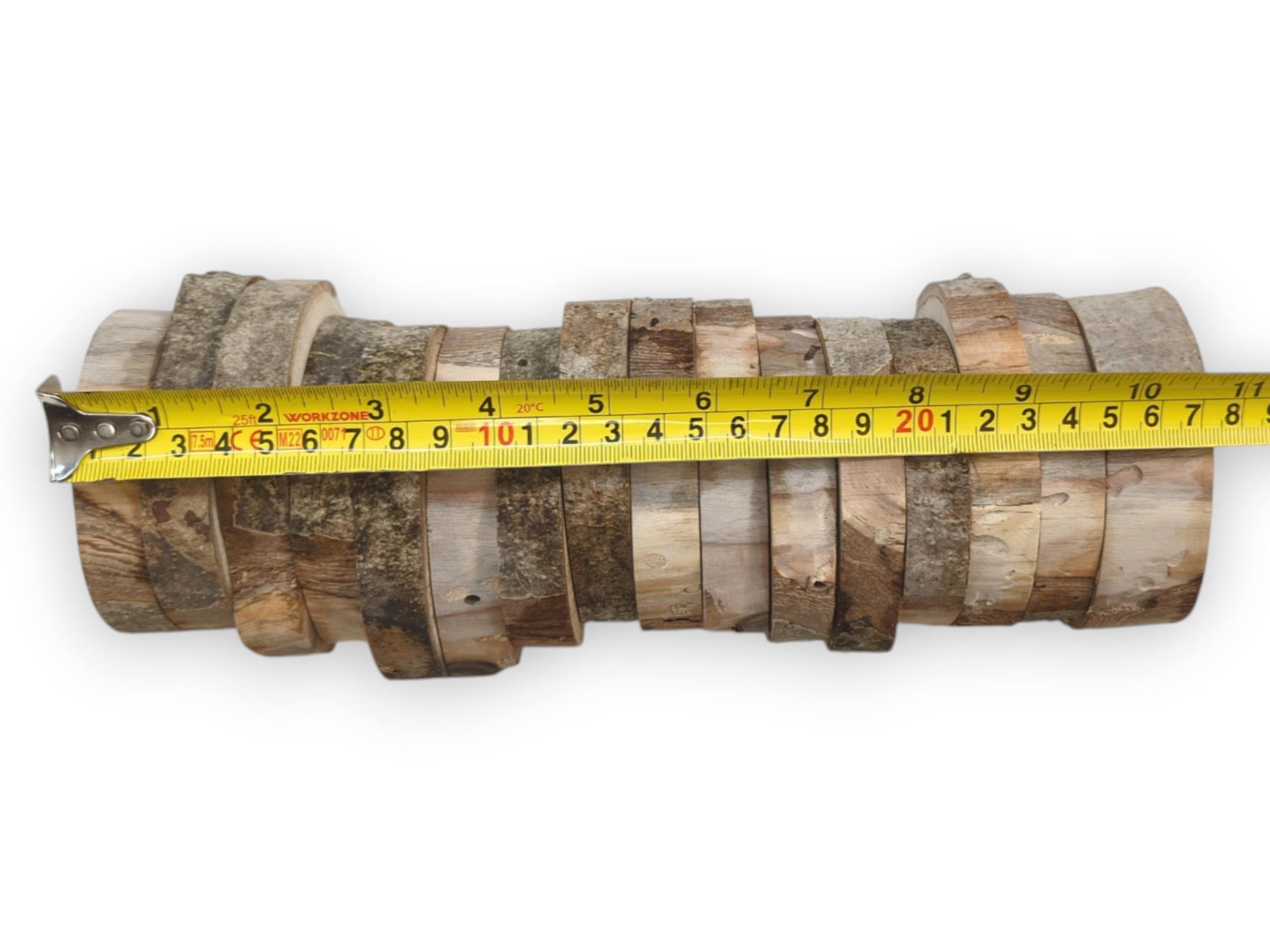 A yellow tape measure sizes a horizontal stack of sixteen varied, bark-edged timber discs.