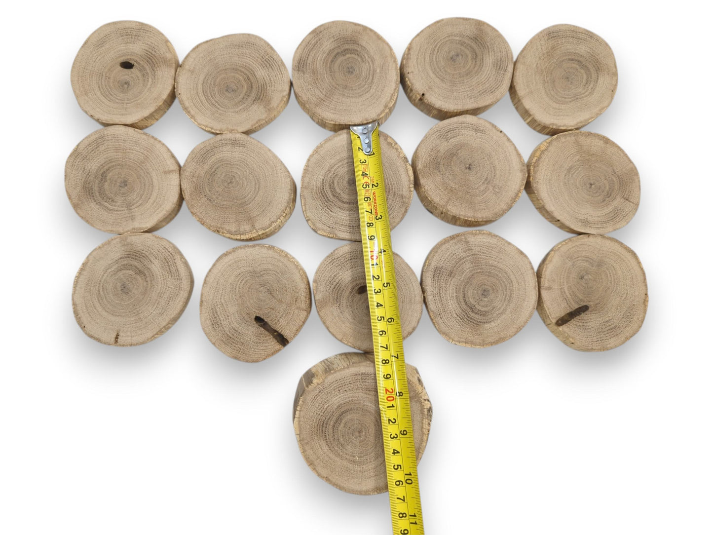 A yellow tape measure is laid over a four-by-four grid of circular wood sections.