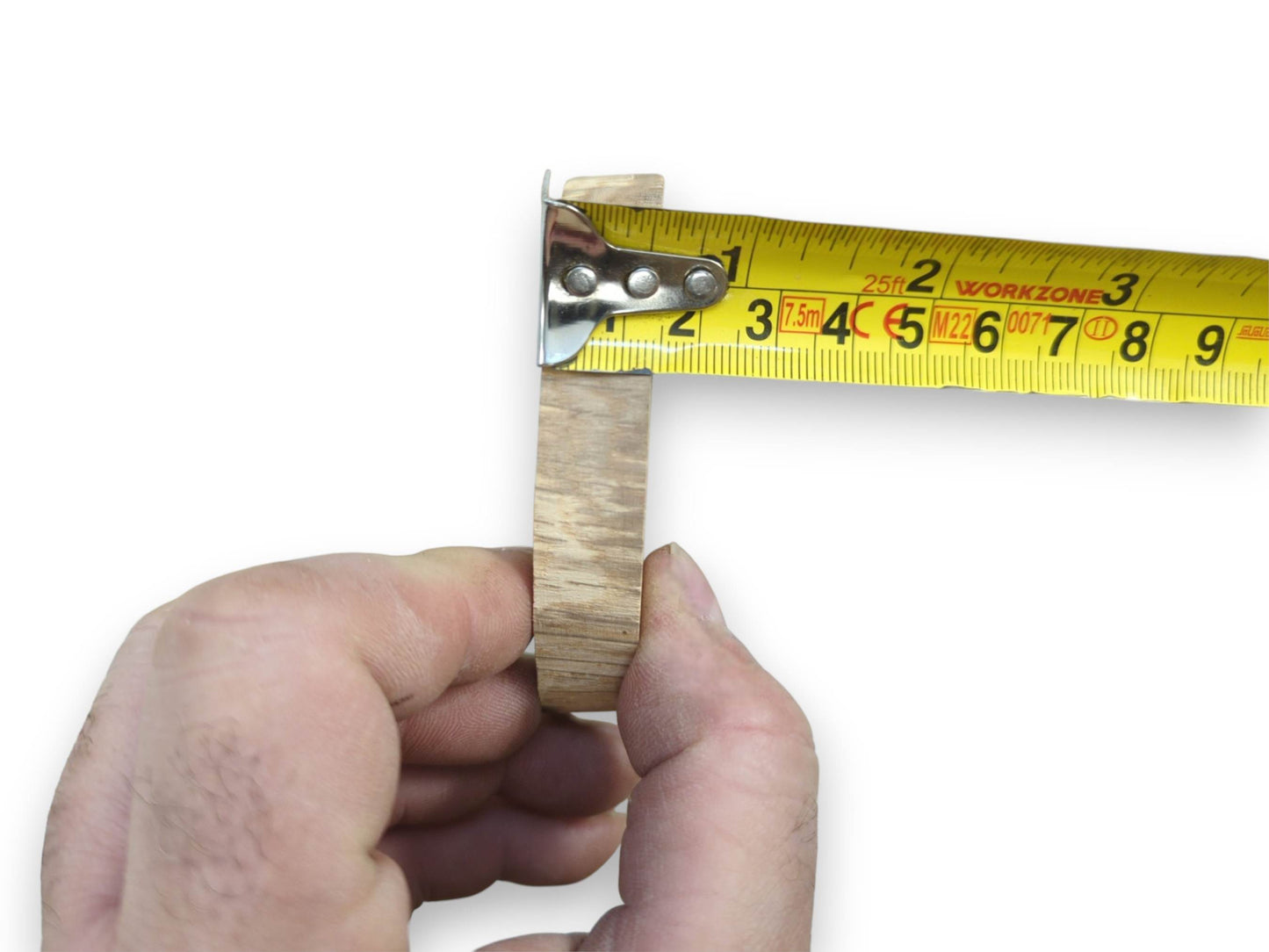 A hand measures the thickness of a small oak round, revealing its linear side grain.