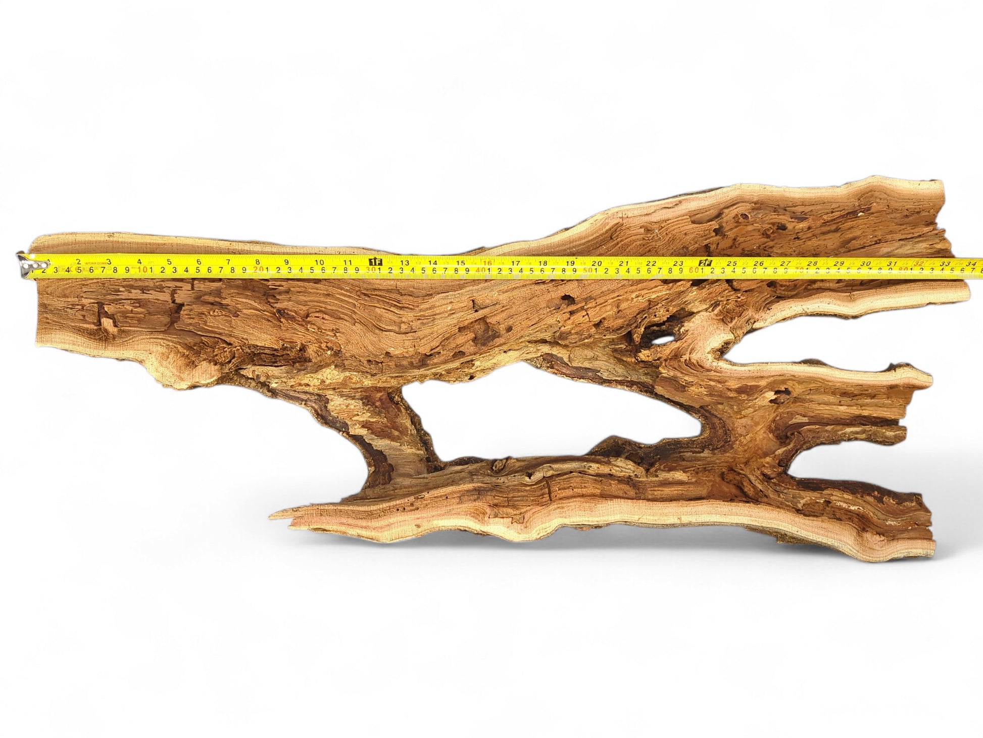 Long, flat, light brown wood piece with detailed grain, several irregular openings, and a yellow measuring tape.