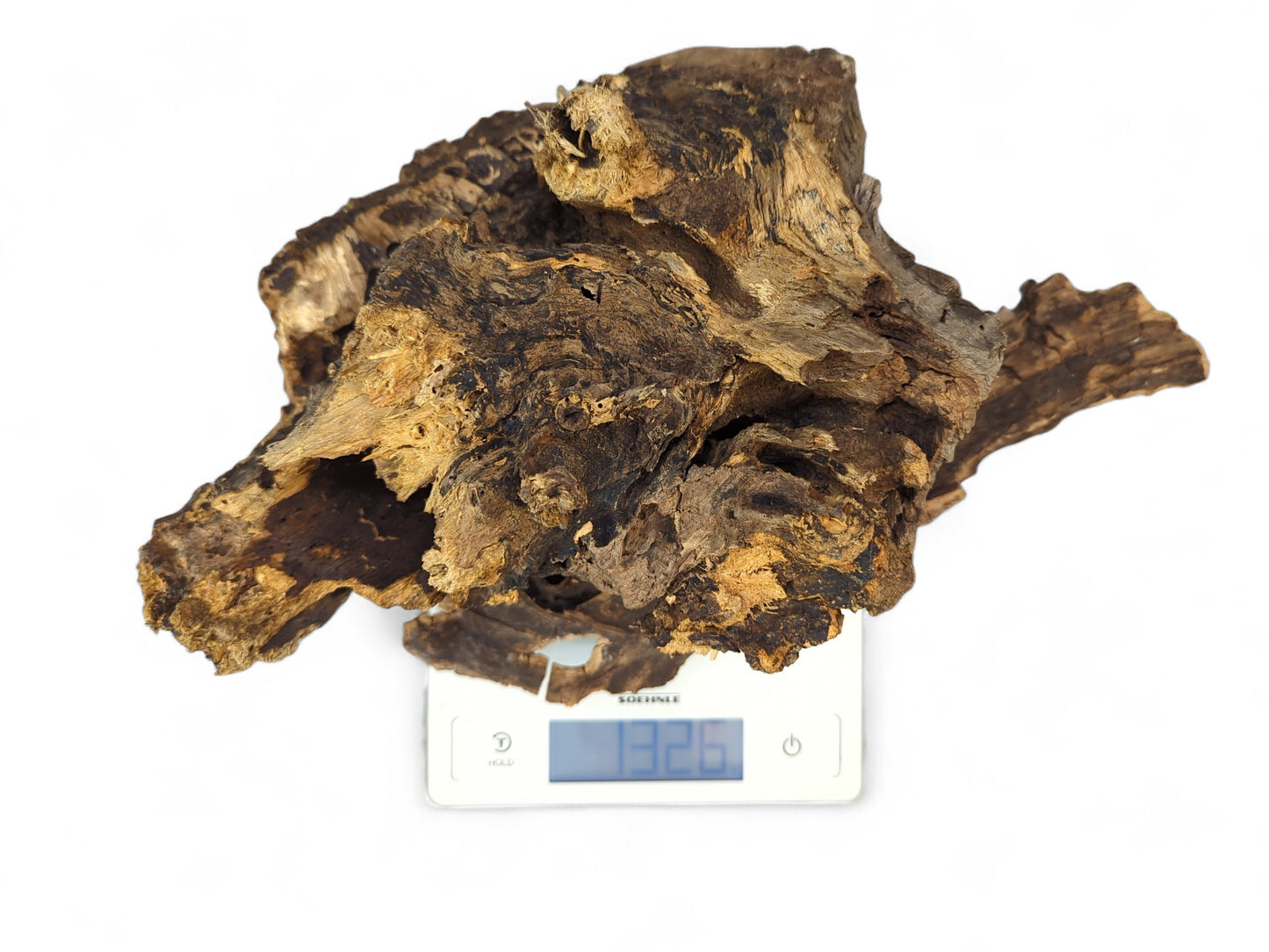 An irregular dark brown, hollow driftwood piece with rough bark, weighing 132.6 grams on a digital scale.