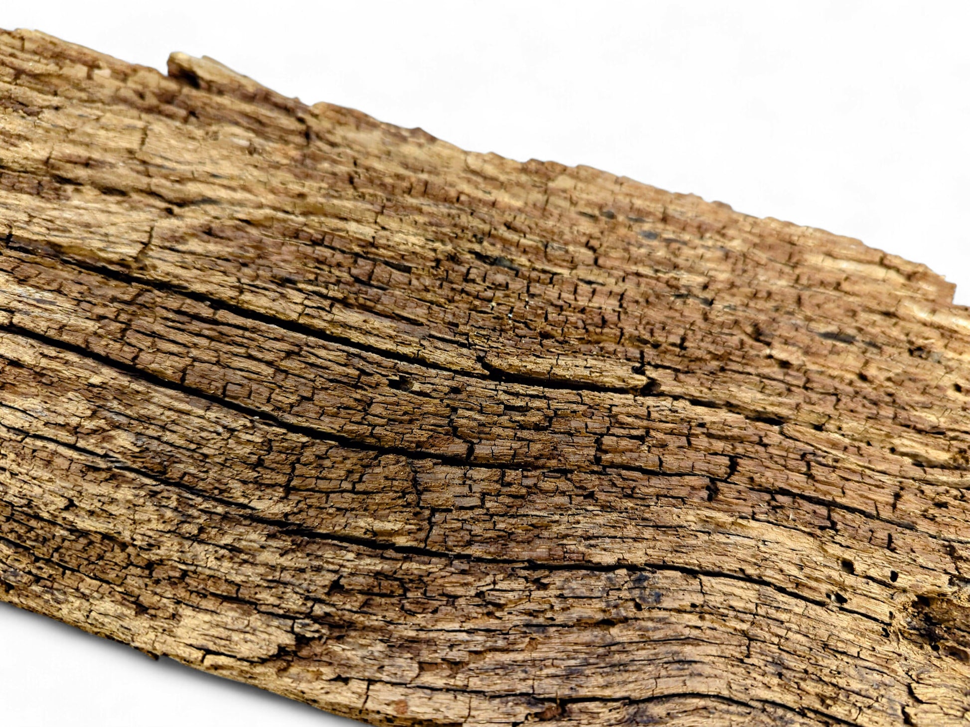 Weathered, dry, brown reclaimed wood fragment displaying deep cracks and a crumbly, flaking surface.