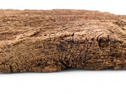 Close-up of an aged, brown reclaimed wood fragment with deep cracks, flaking texture, and a prominent knot.