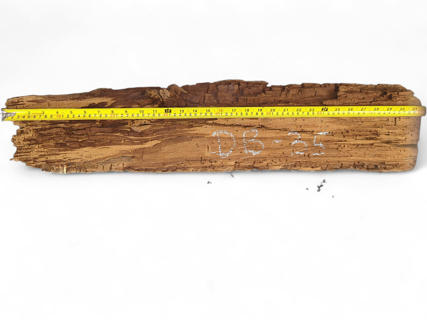 Reclaimed, light brown wood fragment showing deeply flaking, crumbly texture, a measuring tape, and "DB-35" marking.