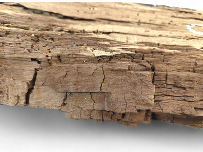 Brown reclaimed wood fragment showing deep cracks, a severely flaking, crumbly surface, and small holes.