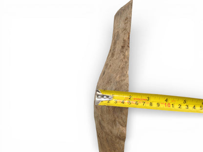 A close-up showing a yellow measuring tape determining the width of a raw, irregular oak piece.