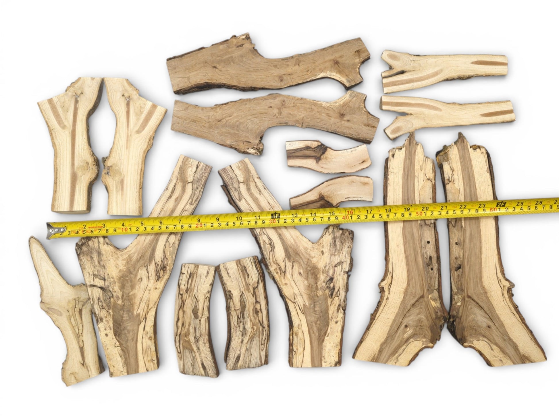 An overhead view of multiple split wood pieces with dark grain, measured by a yellow tape.