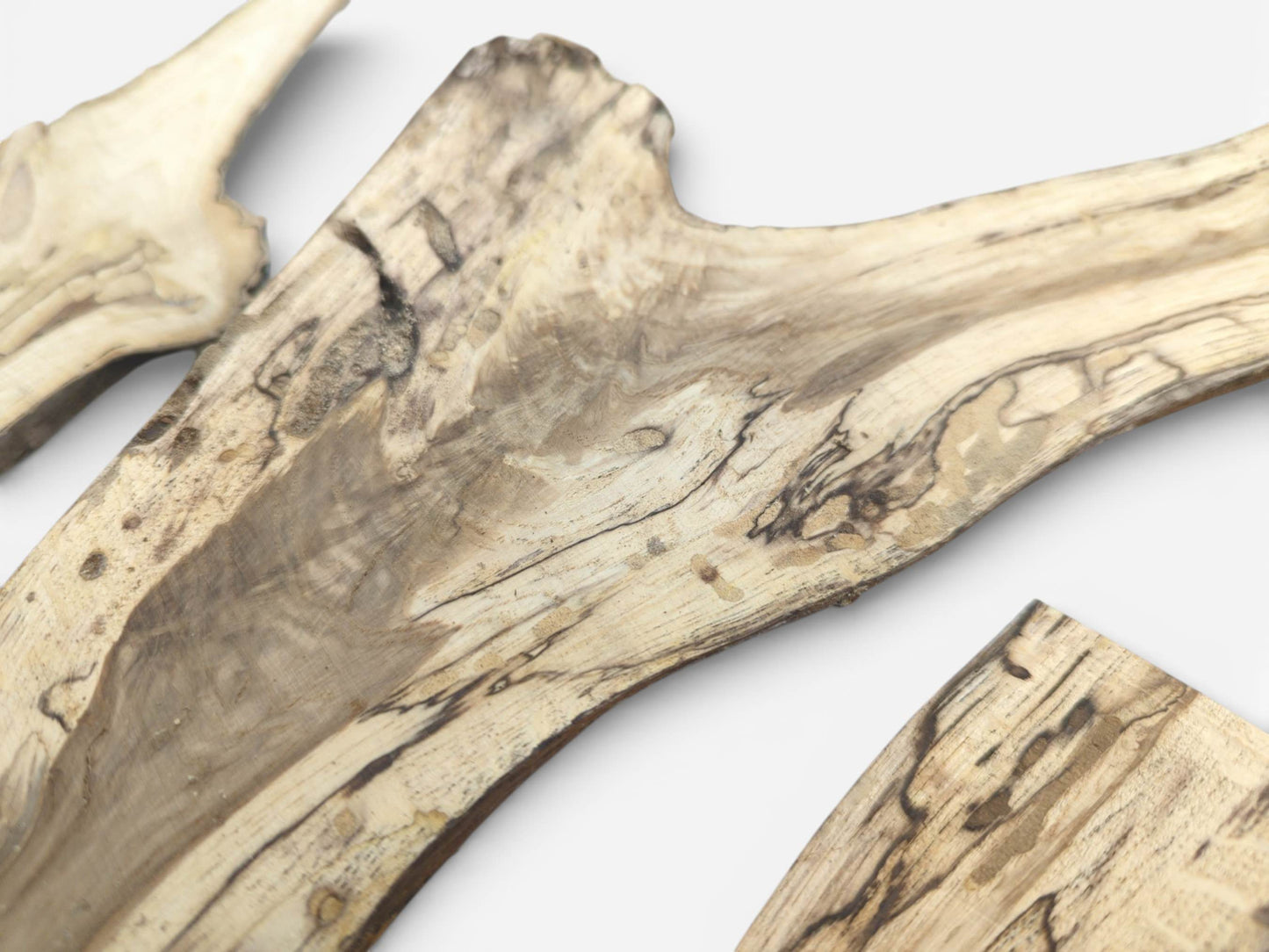 A close view of split wood sections displaying prominent, dark marbled grain on light-colored wood.