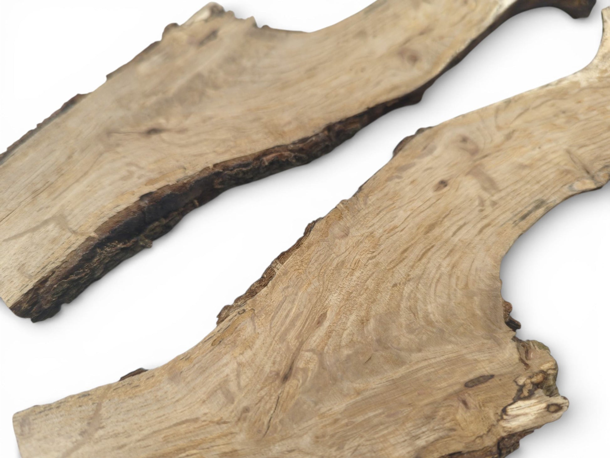 An angled, close-up perspective of two natural wood slabs with visible grain patterns and raw bark edges.