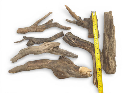 A top-down arrangement of seven weathered wood pieces shown with a tape measure for size reference.