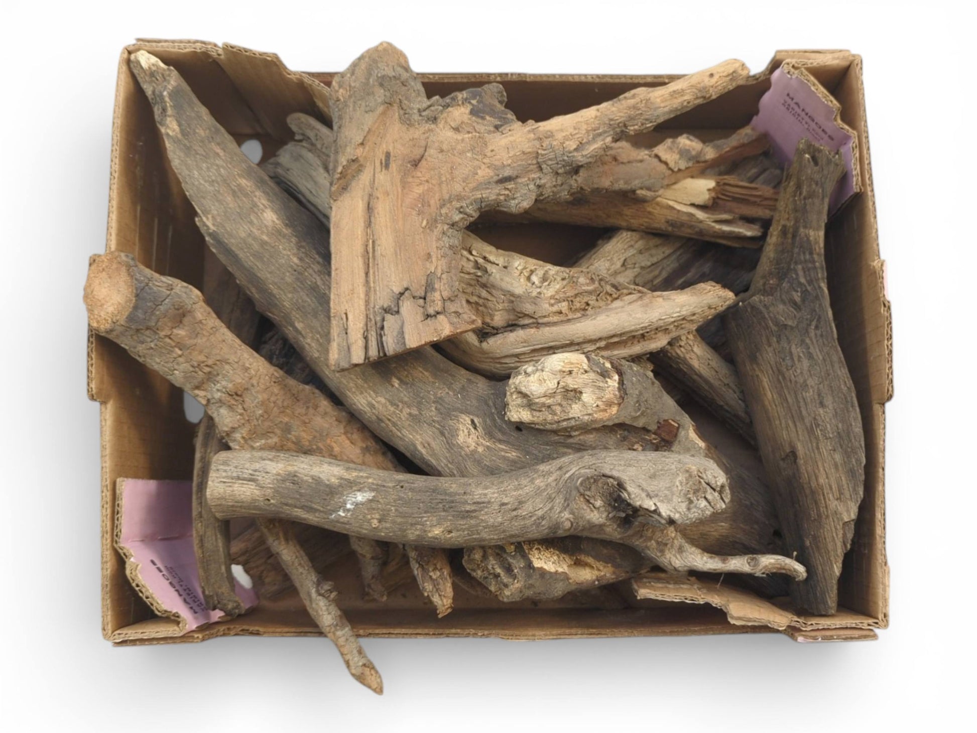 An open cardboard box viewed from directly above, holding a variety of aged, untreated wood pieces.