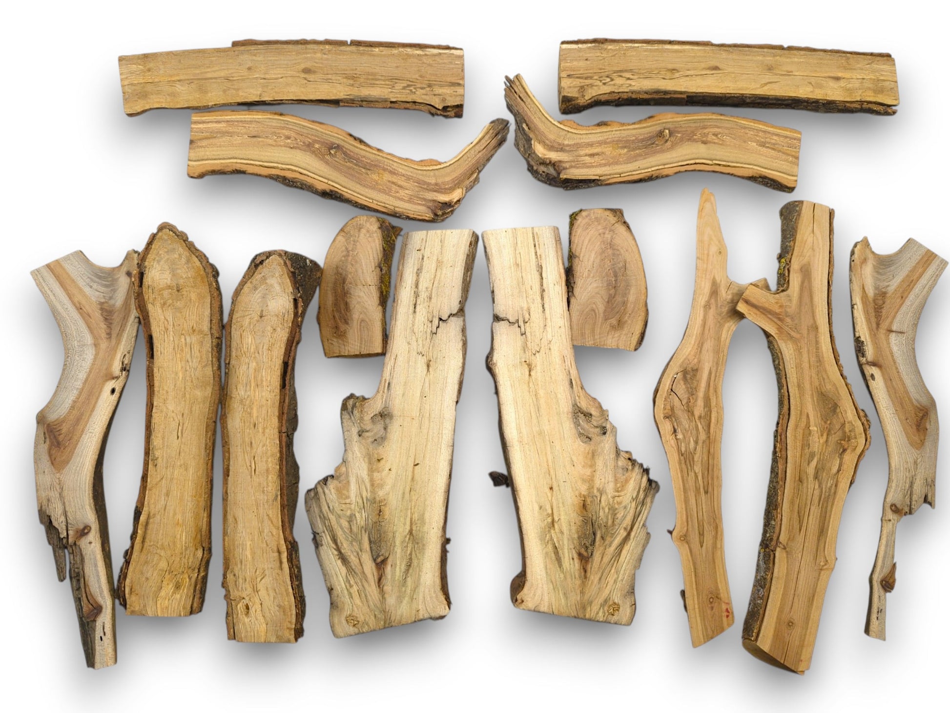 An overhead view of an assortment of halved timber pieces, showcasing varied irregular shapes and natural edges.