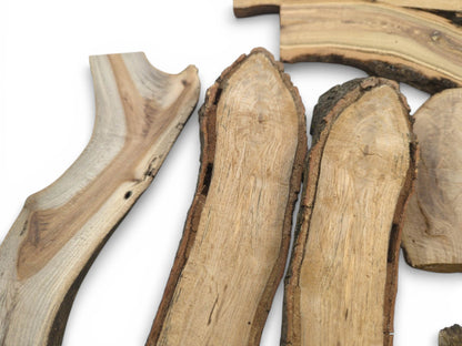 A close-up assortment of split timber pieces, revealing their grained surfaces and rough bark edges.