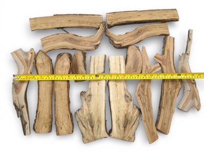 An overhead display of halved branches with a yellow measuring tape indicating their assorted lengths.