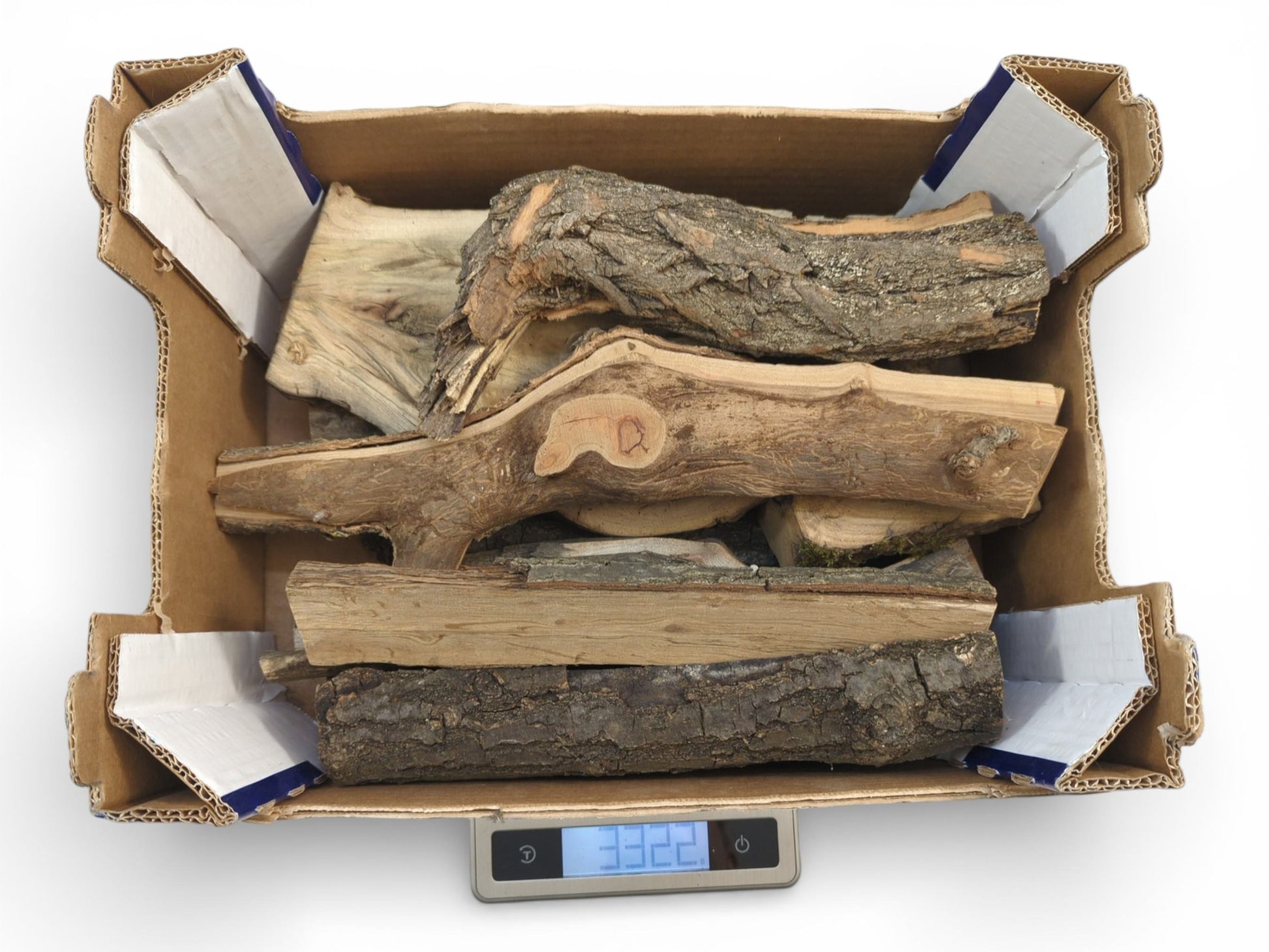 A brown cardboard box containing assorted split wood logs is weighed on a small digital scale.