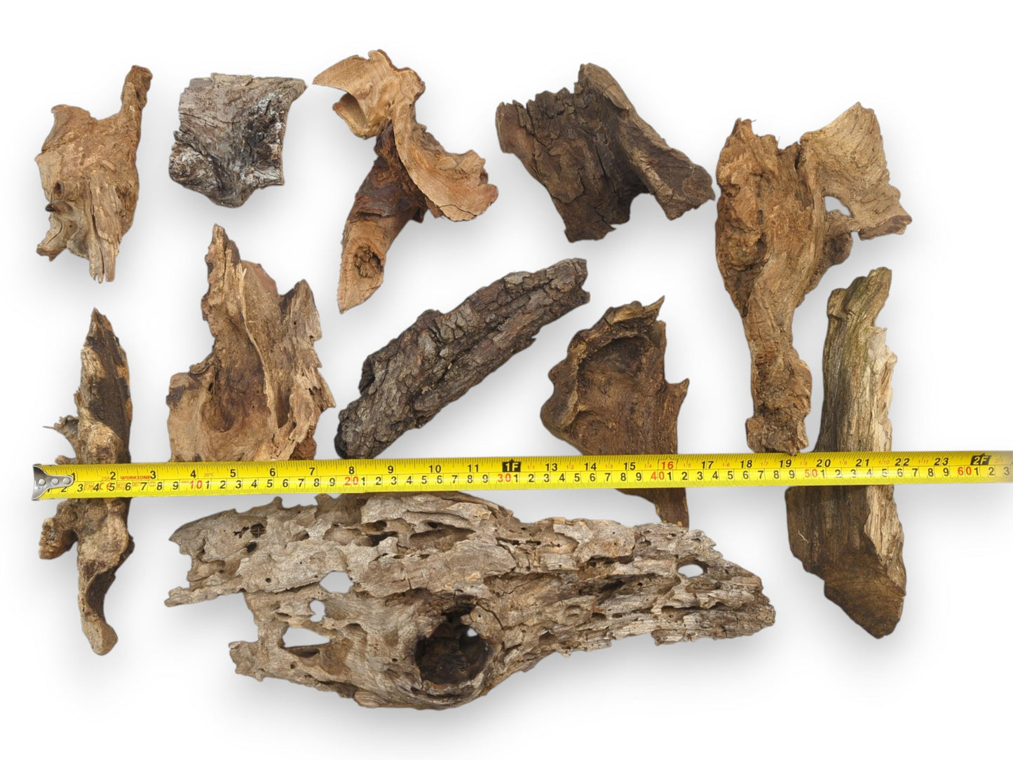 An assortment of natural raw wood chunks with a yellow tape measure indicating their various lengths.