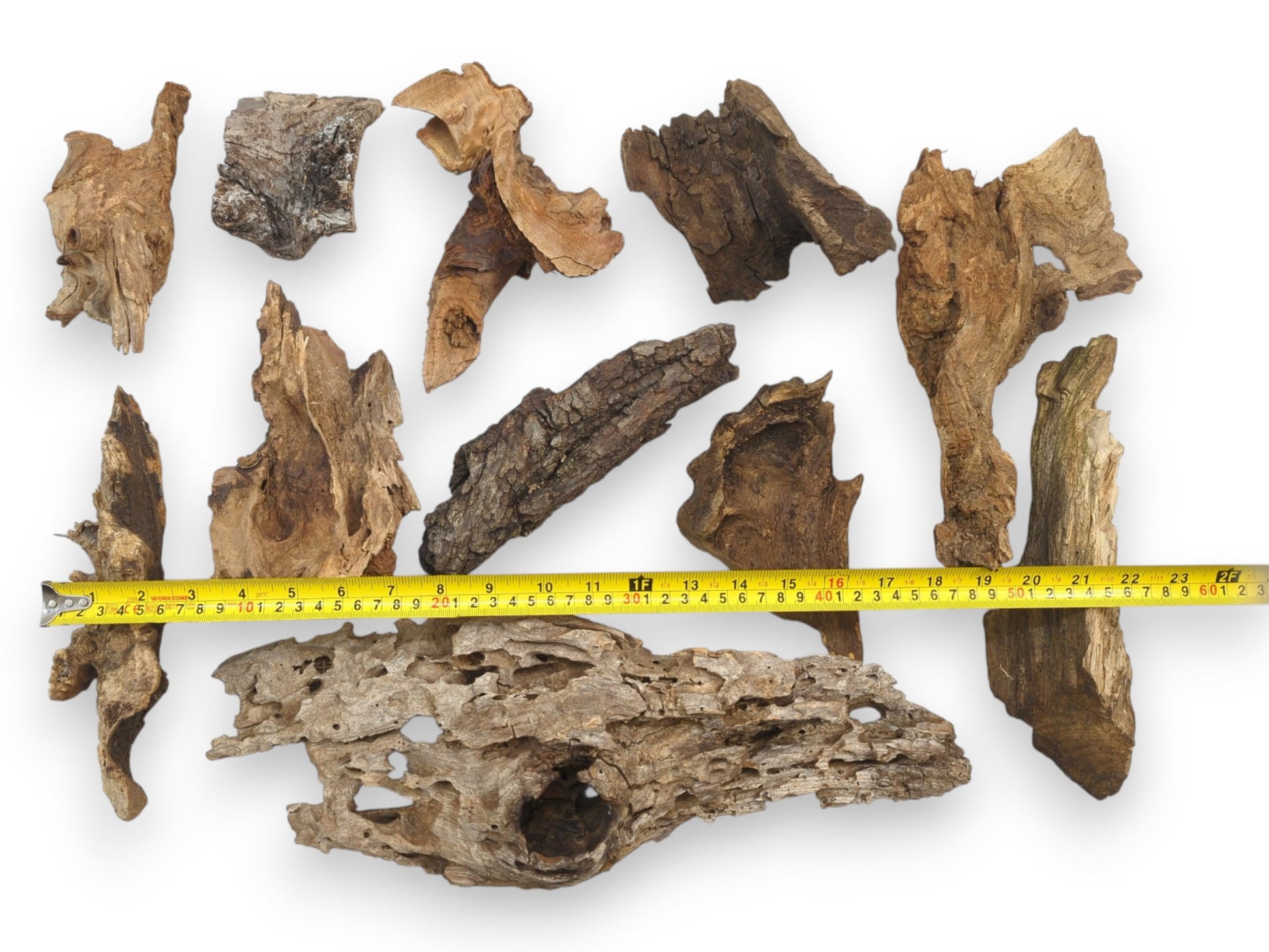 An assortment of natural raw wood chunks with a yellow tape measure indicating their various lengths.